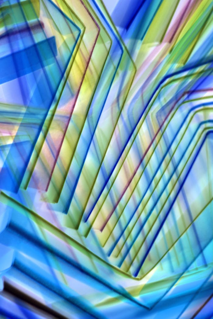 Dynamic abstract art featuring layered geometric shapes in blue, green, and yellow hues.