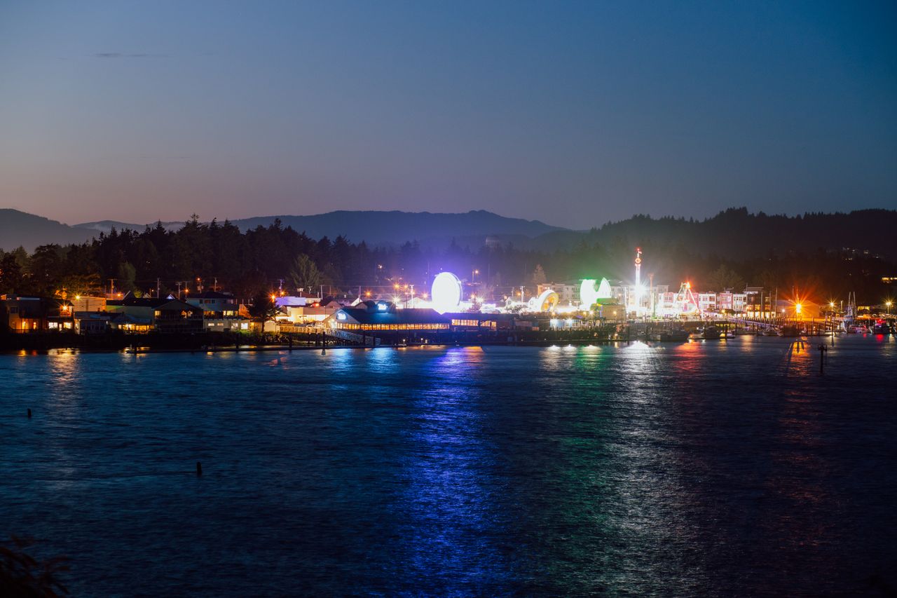 services-02 A vibrant view of Florence, Oregon's illuminated waterfront at dusk with colorful reflections.