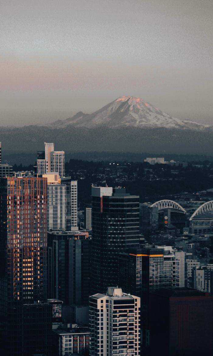 A scenic view of Seattle's skyline with Mount Rainier in the background at dusk.