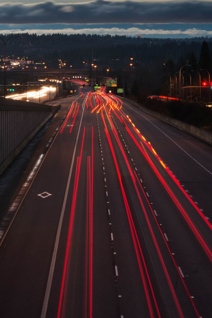 services-01 Dynamic night photo of a highway with red light trails showcasing fast-moving traffic.